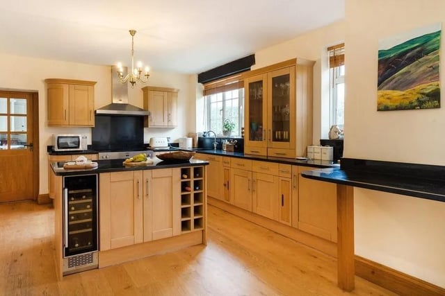 The kitchen features a range of wooden units and a central island, as well as black granite worktops. Picture: Savills - Haywards Heath.