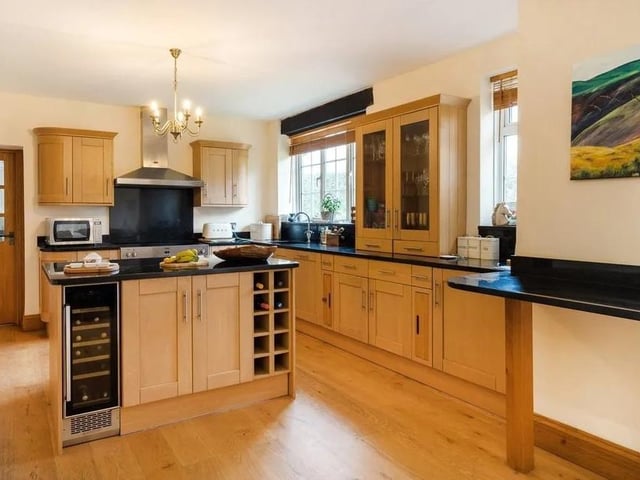 The kitchen features a range of wooden units and a central island, as well as black granite worktops. Picture: Savills - Haywards Heath.