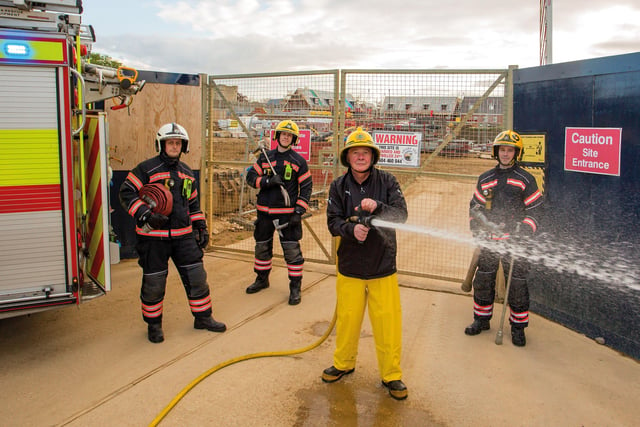 John  wore his original helmet for the reunion photo, but his yellow plastic trousers were changed as they had melted. He was joined by his former colleagues for the reunion (from left) Watch Commander Steve Peacock, firefighter Rob Woodcock and firefighter Tom Bishop.