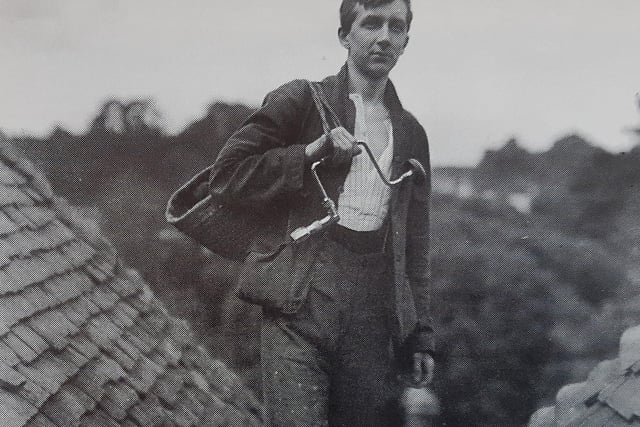 An unusual portrait in which a young workman stands in a valley framed by roofs