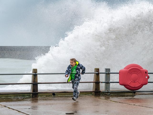 A boy runs for cover as waves slam against the harbour wall at Newhaven