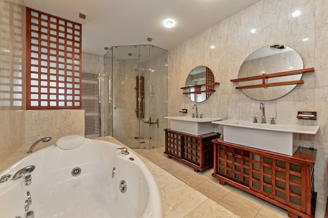 The main bathroom features a white suite comprising spa bath, walk-in double shower enclosure, two wash hand basins with storage under, bidet and low-level WC, tiling to all walls, window to side, heated towel rail, tiled flooring,