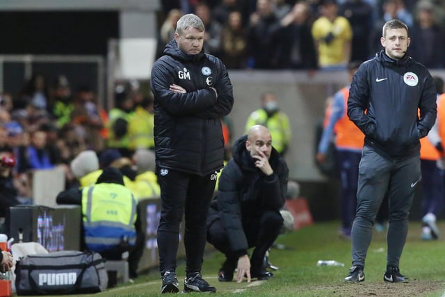 Posh boss Grant McCann and Manchester City manager Pep Guardiola (kneeling) on the touchline.