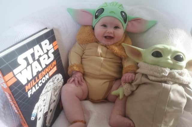 Billie Aurora Cooper, only five months old, putting the baby in Baby Yoda.