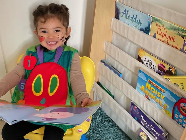 Eliza Sembie-Ferris, aged two, enjoying reading a book dressed as the Hungry Caterpillar before school this morning.