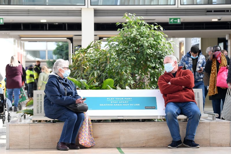 Here's two shoppers taking a well-earned break from queueing to have a socially distanced chat on a bench.