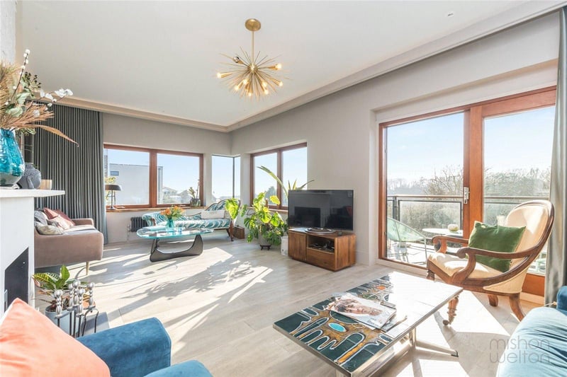 The spacious living room has been designed with a fabulous frameless corner window, and large original windows to embrace the south-westerly views and amazing sunsets across to the sea and the woodlands.