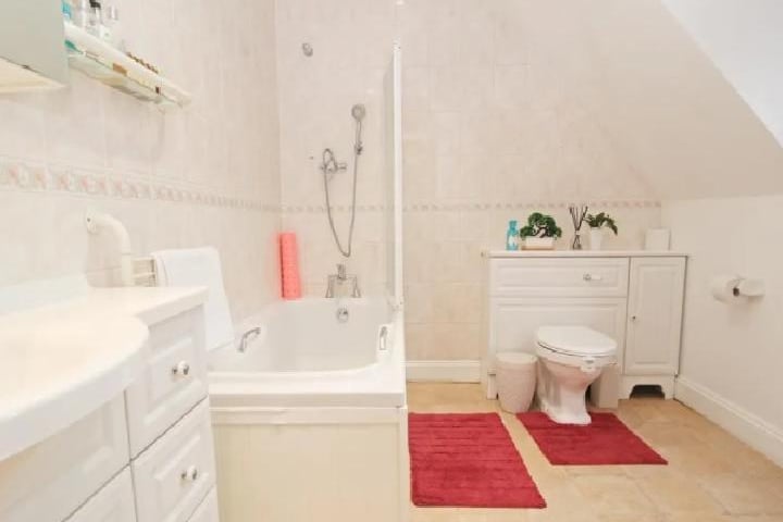 This bathroom is one of three on the property. The bath doubles as a shower, with a vanity sink and WC also contained. There's plenty of storage for beauty products and toiletries.