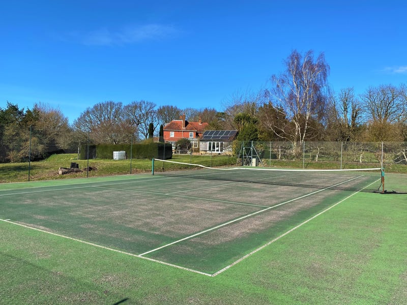 The grounds also include a tennis court (pictured), a four-acre paddock and a wildflower meadow