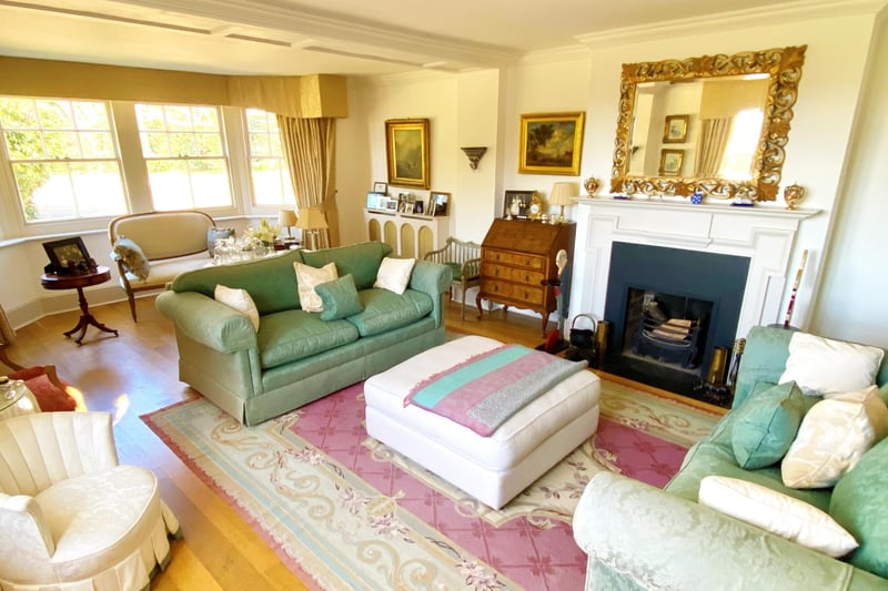 The drawing room with open fireplace and windows overlooking the garden