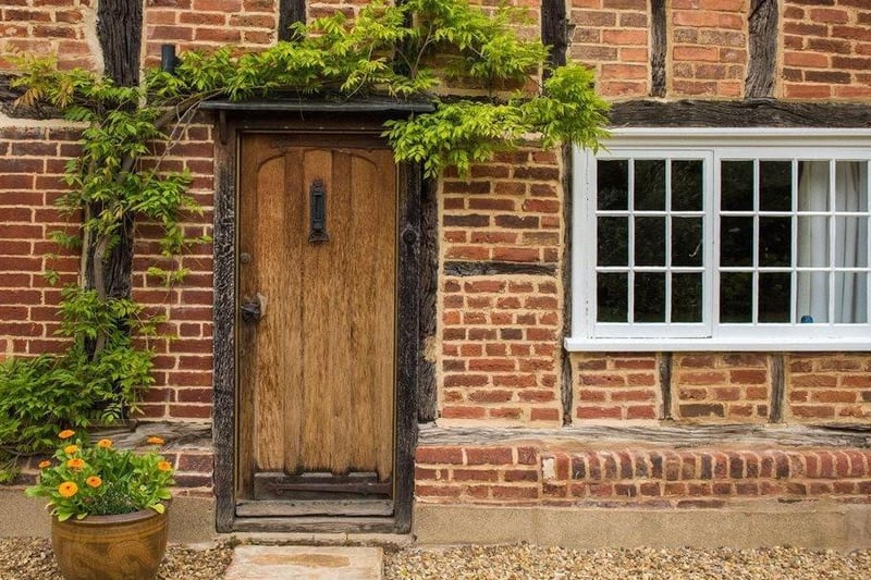 This entrance boasts an oak wooden door surrounded by brickwork and wooden beams