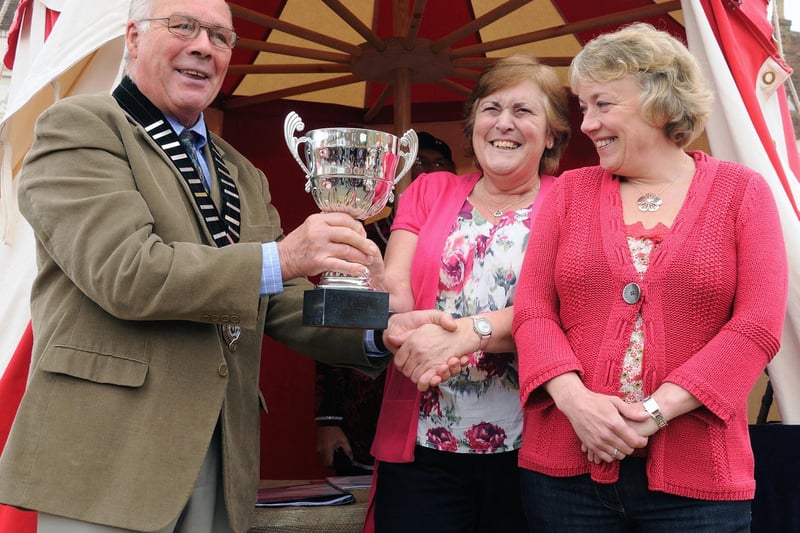 Battle Town Mayor Cllr Ron Harris presents the winning trophy for the best dressed shop window (Medieval theme) to Vicky and Cherry of Day Lewis Pharmacy.