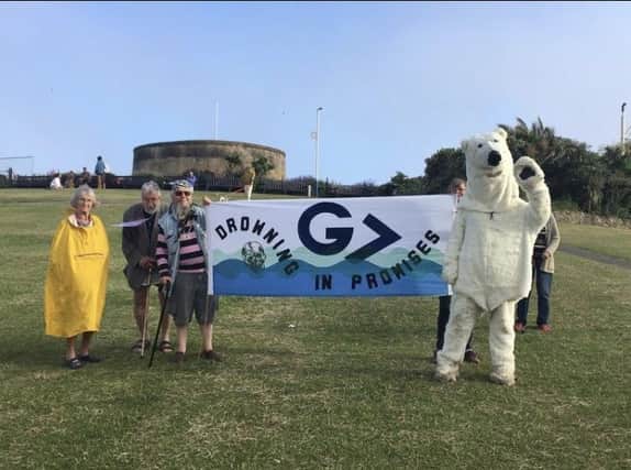 Members of Extinction Rebellion holding up a banner by the Wish Tower in Eastbourne. SUS-210614-094233001
