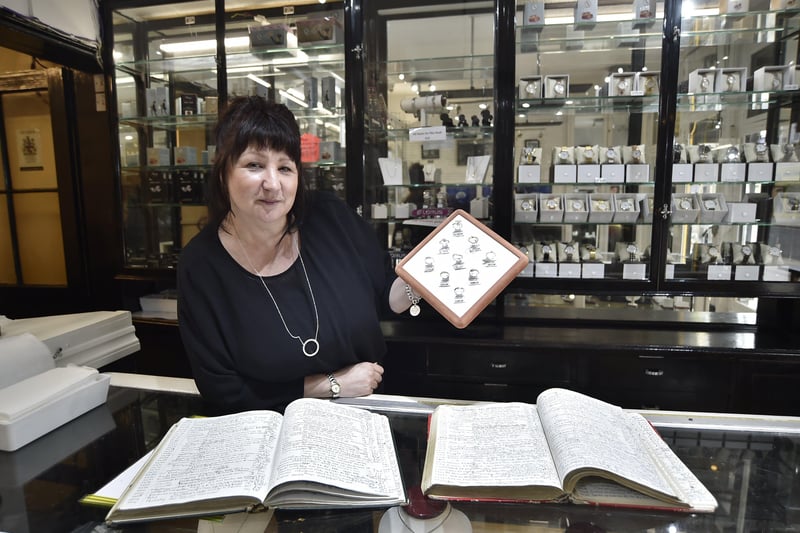 Sales assistant Tracey Thompson with some of JW D'arcy's early account books. EMN-210630-161810009