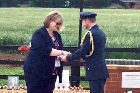 Kirsty Eales, head of Overstone Combined School, receives the ensign from Wing Commander Steve Thornley