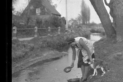 Dorothy Goode and her dog fetching water from the village stream.