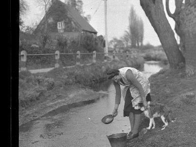 Dorothy Goode and her dog fetching water from the village stream.