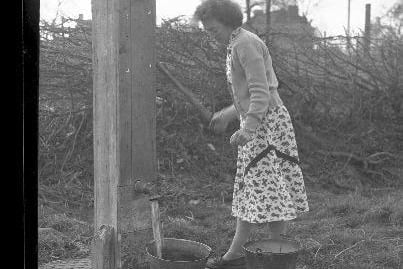 Nora Edginton using the pump on The Green, Dodford.