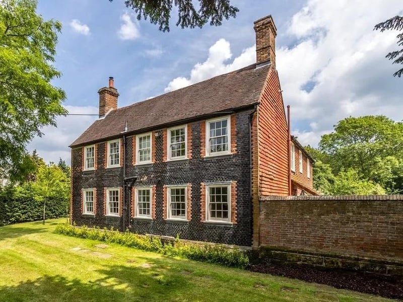 The home's facade of tiles and symmetrical sash windows with red brick window dressings is typical of the Georgian era.