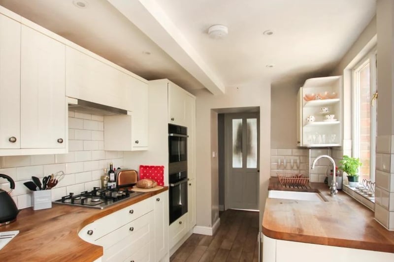 The kitchen features wooden worktops and a butler sink