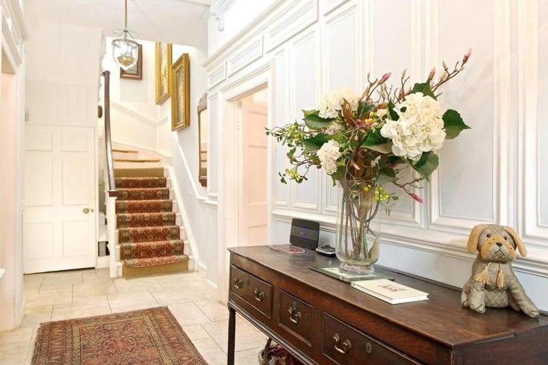 This elegant hallway has a wooden staircase with a polished handrail