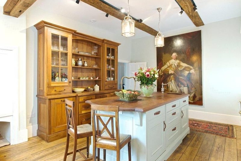The island in the kitchen has a walnut top, complete with cupboards on both sides, a prep sink and seating