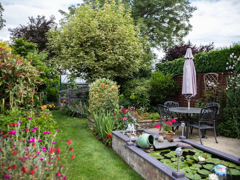 Gill and Malcolm bought themselves a garden archway as a retirement present to each other. 
The archway looks incredibly authentic and adds to an already beautiful and serene garden.
Gill said: “It’s a busy garden and a seven-day-a-week job but we love it.
“It has kept us sane throughout the pandemic.”
Gill and Malcolm’s garden also includes a pond with fish and a vegetable patch where they grow potatoes, peas, cabbages and more.
Gill added: “It’s our garden and I don’t know what other people have so I wasn’t sure about putting it into the competition.
“I was completely shocked when Richard knocked on the door to say we had won.
“We’re very honoured.”
Photo: Kirsty Edmonds.