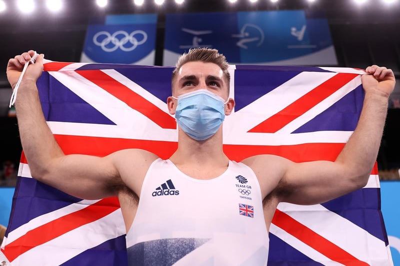 Max Whitlock waves the flag after he was confirmed as the Olympic pommel horse champion