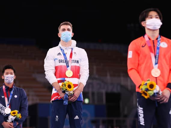 Max Whitlock stands on the top podium after he defended his Olympic pommel horse title