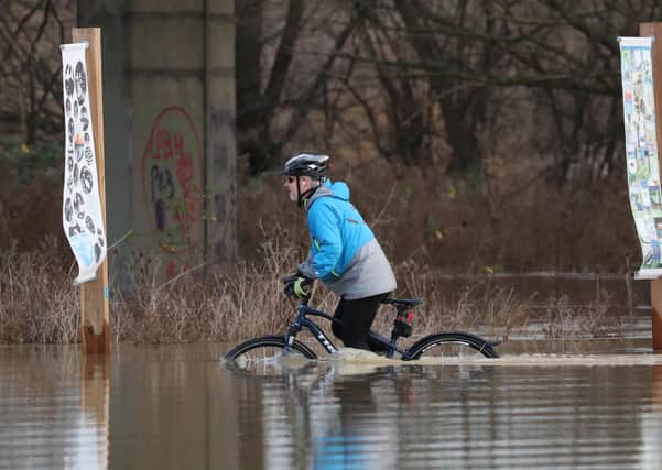 A person cycles through floodwater at Orton as the area is completed flooded as the River Nene burst its banks in December 2020. Picture: Paul Marriott