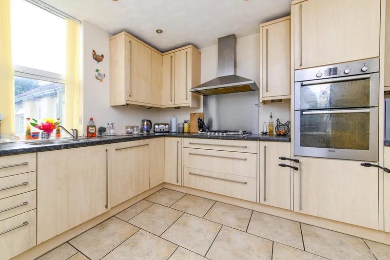 The fitted kitchen featuring double electric oven, five ring gas hob with cooker hood over