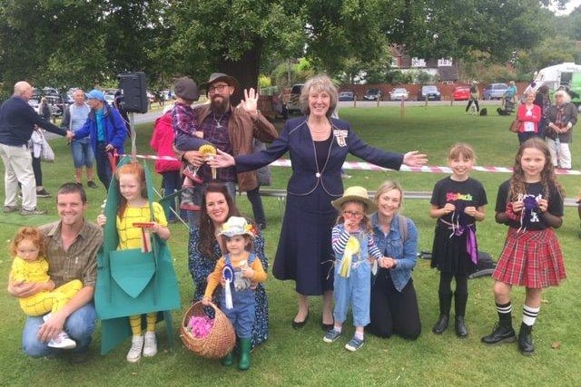 Fancy dress winners. judged by the Lord Lieutenant. Maisie and Ruby Jordan as corn on the cob, with father John came first. Second was an enthusiastic harvester of fruit and flowers Evie Crawdon.