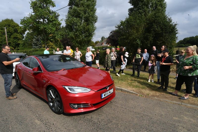 Friends and family look on as the Tesla convoy visits Harvey Ahern-Sutliff.