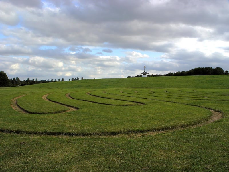 Near the Peace Pagoda is apiece of landscape architecture called the Willen Labyrinth. The turf maze based on an enlarged version of the Saffron Walden Rosicrucian Maze. At its centre is an oak tree and in each of the four lobes is a bronze face designed by sculptor Tim Minett. The maze unifies the faces in peace and places them in the context of dominant nature, symbolised by the oak tree.