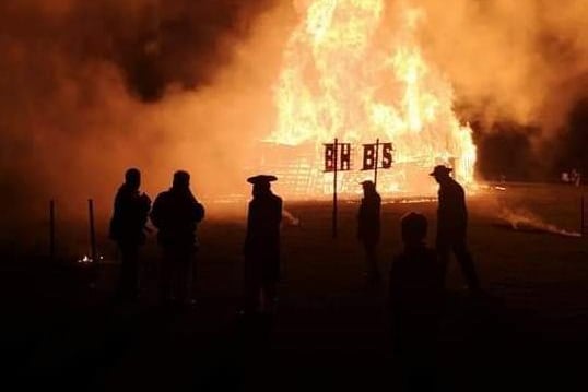 Burgess Hill Bonfire Society members silhouetted against the roaring flames.