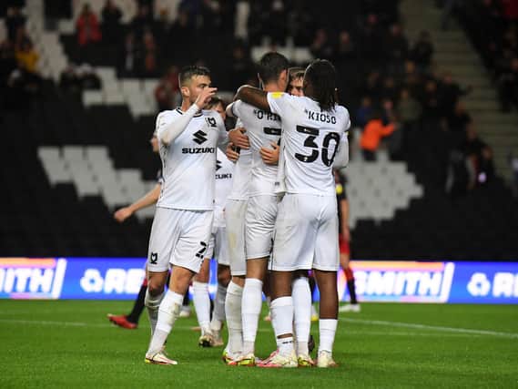 Scott Twine is mobbed by his MK Dons team-mates after scoring his first goal