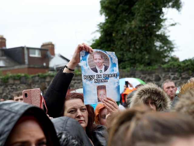 A member of the public holds a poster with the message 'Rest in peace Noah'.