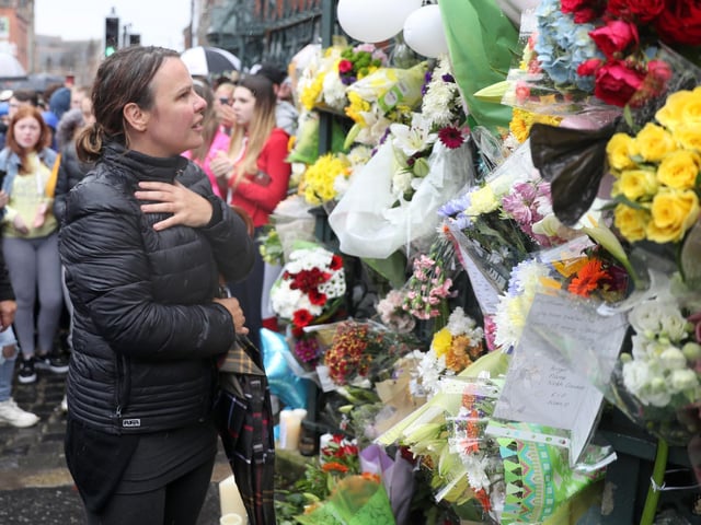 Noahs aunt Niamh looks at the floral tributes to Noah on the gates of his school, St Malachys.