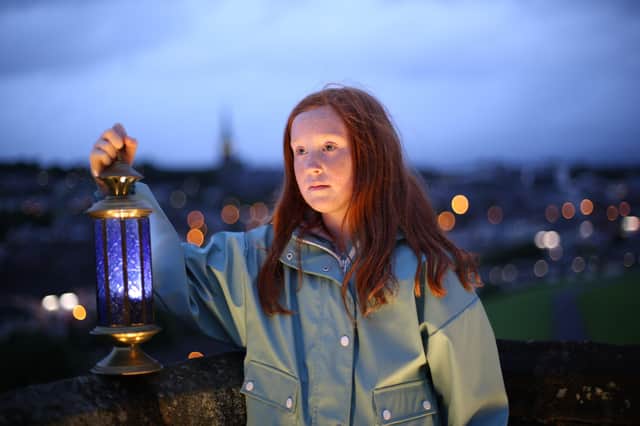 Ten-year-old Millie McHugh, holds a candle in memory of Nobel laureate John Hume