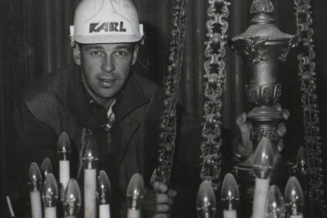 Trevor Smyth works on the chandeliers in the Great Hall at Stormont as steel beams are put in place during the refurbishment of the building after fire