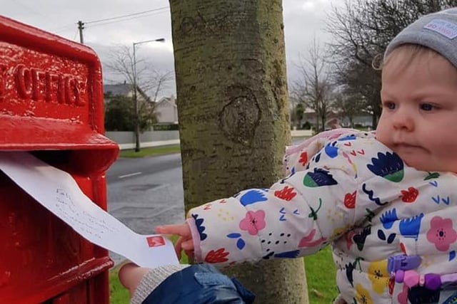 One-year-old Olivia McLaughlin makes sure her letter to Santa gets into the post box.
