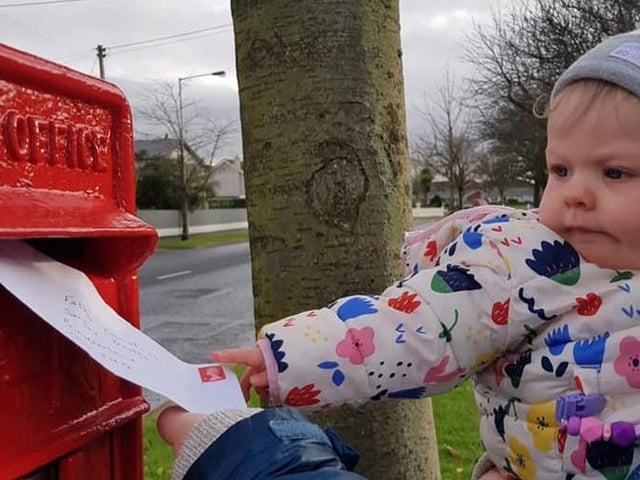 One-year-old Olivia McLaughlin makes sure her letter to Santa gets into the post box.
