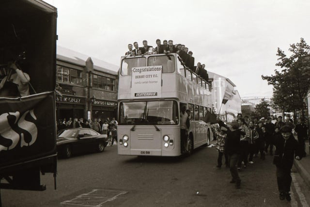 Derry City players look on from the top of their bus as it makes its way through a crowd of fans on Foyle Street.