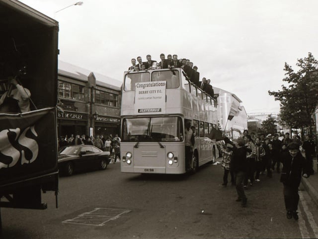 Derry City players look on from the top of their bus as it makes its way through a crowd of fans on Foyle Street.
