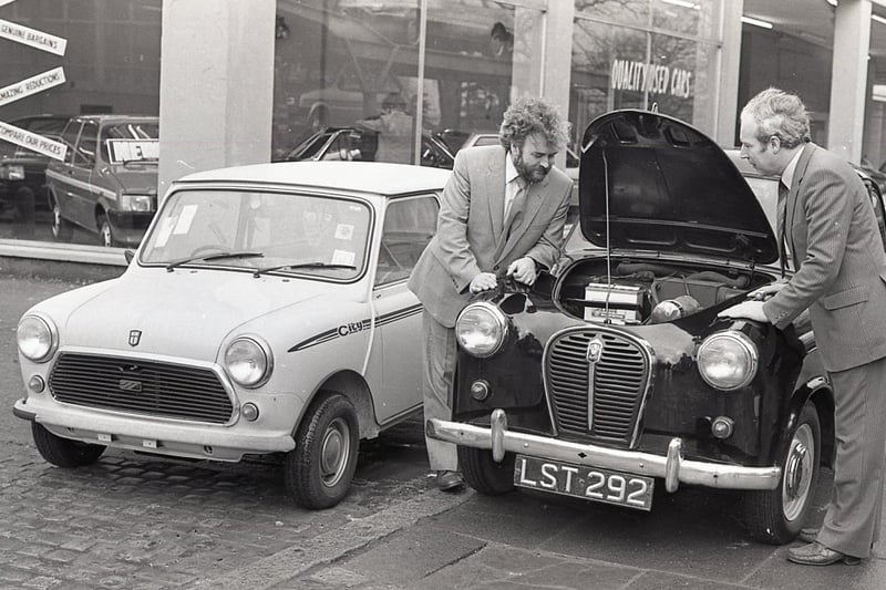 The changing face of motoring in 1982. Mr Mervyn Stewart, right, whose company had been awarded a BL franchise, is pictured outside new showrooms on the Ormeau Road, Belfast, with Mr Sam Bickerstaff, one of his first customers when he founded the business in 1957. They are seen here examining an Austin A35 of that era and its modern equivalent, the Mini City.  Picture: News Letter archives