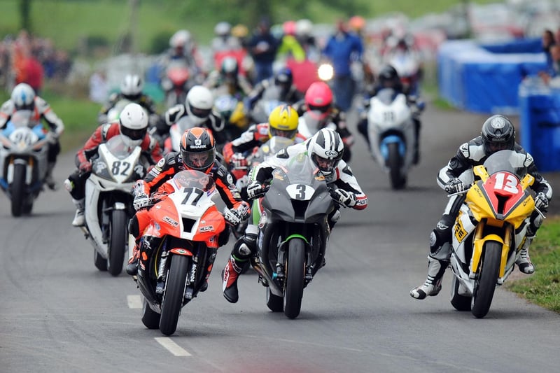 The start of the Superbike race as Ryan Farquhar (77) gets the jump on Michael Dunlop (3) and Adrian Archibald (13) with Derek Sheils (82) and John Burrows (partially obscured) in behind. Dunlop won the race and set a new outright lap record of 109.297mph, shattering the previous benchmark of 106.930mph.