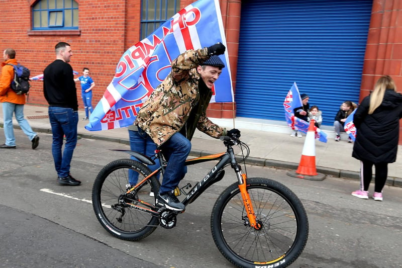 A Rangers fan waves a flag outside of the Ibrox Stadium as he celebrates Rangers winning the Scottish Premiership title