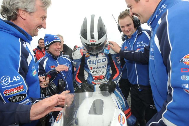 William Dunlop is congrtulated by his Tyco Suzuki team after edging out brother Michael to win the first Superbike race.