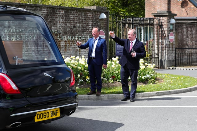 Actors Paddy Jenkins and Damon Quinn join family and friends to raise a toast outside Roselawn Cemetery in Belfast as the hearse arrives during the funeral of actor BJ Hogg
