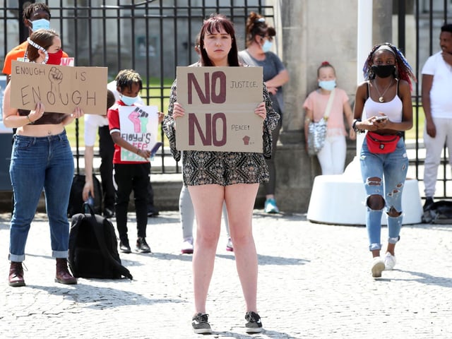 'No justice, no peace' reads a placard held by a young woman at the Black Live Matter solidarity rally in Belfast on Monday.